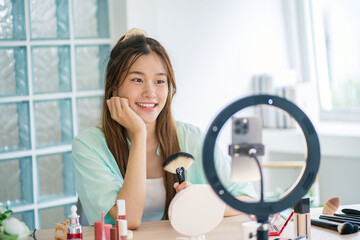 Fototapeta na wymiar Beauty influencer Asian girl makeup artist applying powder foundation by brush. Beauty influencer asian girl video online marketing live streaming .
