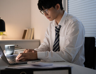 Asian businessman working on laptop in night office. dark late night at home office online meeting work hard concept.