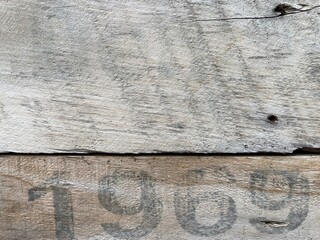 On a weathered wooden board is printed in black paint the number 1969