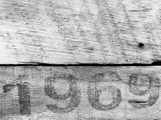 On a weathered wooden board is printed in black paint the number 1969