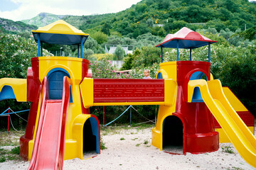 Little girl on a playground with slides at the foot of the mountains. High quality photo