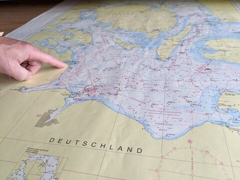 Hand pointing at the sea charts for naval navigation. Radio and radar equipment with sea map for navigation on the boat