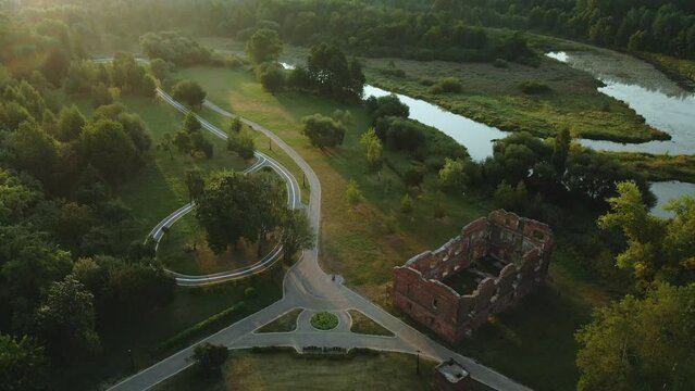 Winding river in the city park. The ruins of an ancient brick building are visible. City park at dawn. Aerial photography.