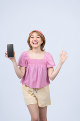 Fototapeta premium Happy smiling asian girl in pajamas and sleeping mask tracking her sleep with mobile app, showing smartphone screen and look pleased, white background