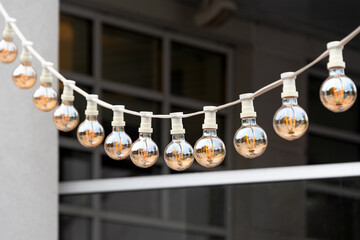 Light garland on the street at daylight. Decoration of the street with vintage Edison bulbs...