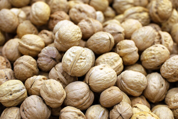 Walnuts heap for background. Dry nuts in shells on a market, protein food for brain health