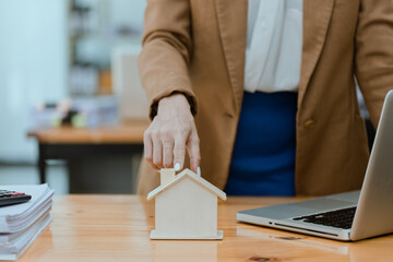 Businesswoman holds a house model, Business home loan and insurance concept.