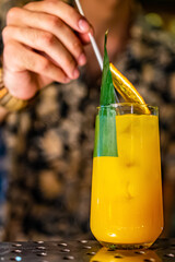 The bartender making cocktail with fruit in a nightclub bar