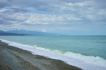 Sea shore with pebbles, wet sea pebbles on the beach and quiet sea surf