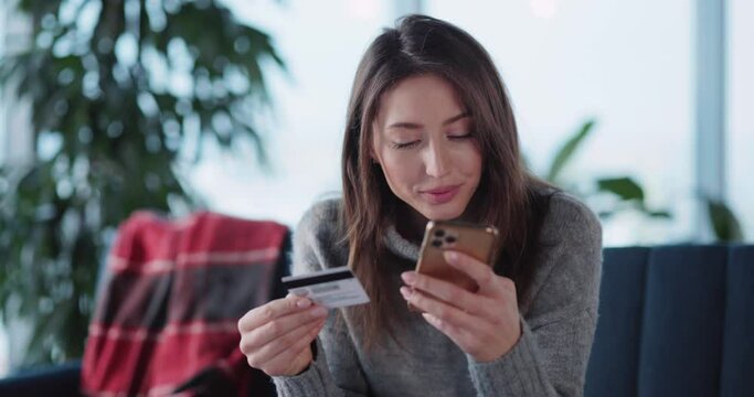 Young caucasian casual woman staying home in winter using smartphone paying for online food delivery service quickly and easily. Credit card payment.