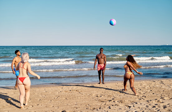 Diverse friends playing with beach ball