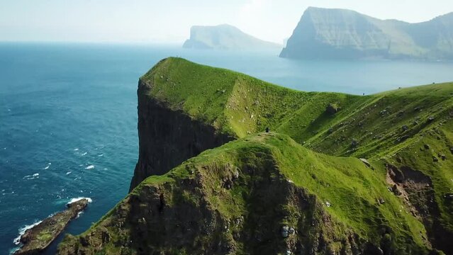 Aerial view of Kalsoy island, Faroe Islands. Amazing Faroese nature, green hills and beautiful rocky cliffs and mountains. Kallur lighthouse. Sunny day in summer. Movie Island in Faroe. 4k footage