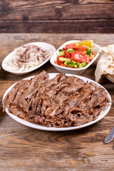 Meat doner kebab on the plate. Turkish meat doner kebab on wooden background. Traditional Turkish cuisine. close up
