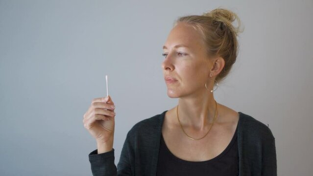 Blonde woman at home performing a nasal PCR self-test for Covid-19