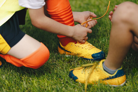 Children Tying Shoe Laces. Kids In Sports Football Team Tying Soccer Cleats. School Boys On Grass Sports Field