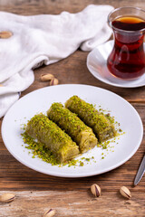 Pistachio baklava. Rolled pistachio baklava on wooden background. Traditional Turkish cuisine. close up