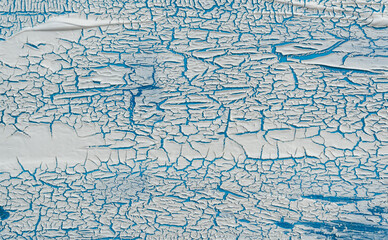 The texture of cracked paint. White texture with craquelure effect on a blue background close-up