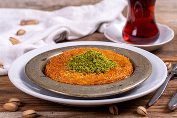 Kunefe. Traditional Turkish cuisine. Kunefe with pistachio on wooden background. close up