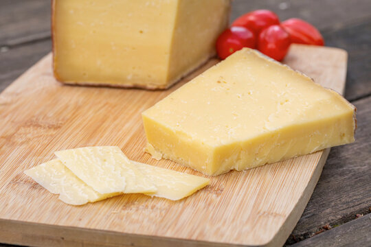 Piece of Italian cheese with cherry tomatoes on cutting board