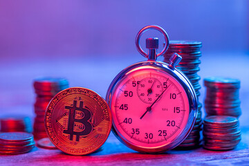 Bitcoin coin and stopwatch with red and blue neon rays. The concept of fast encryption