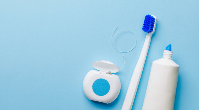 Toothpaste with dental floss and a toothbrush on a blue background. Copy space for text. mockup