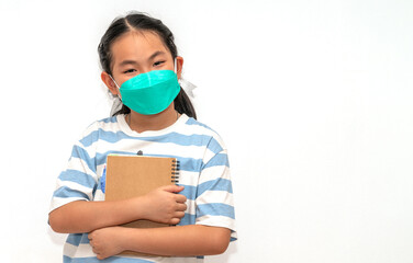 Cute student Asian child girl holding a book, wearing face mask for protection in era of covid-19, isolated student child girl on white background, concept for back to school.