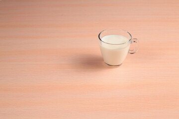 White Beverage in a Glass Cup on a Wooden Tabletop. Milk in a Transparent Mug on a Table.