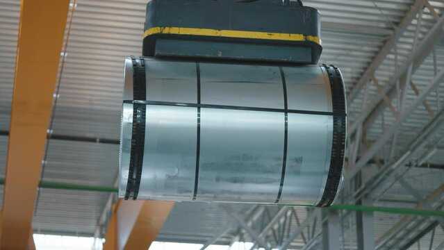 Loading sheet metal in a warehouse using a crane and an electromagnet. Fast work of the warehouse, rolled metal products.