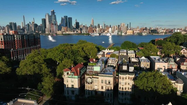 Brownstone homes and apartment buildings. Aerial with Midtown Manhattan NYC skyline in summer.