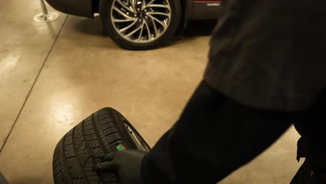 Mechanic checking tire tread depth, panning shot. Repairman technician car service center garage. Shot on 4k SONY A7SIII.
