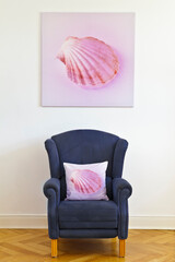Create your own art concept: square canvas print of a pink shell picture and a blue wing chair with a throw pillow of the same photo.