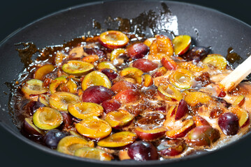 The process of boiling plum jam in a cast iron pan