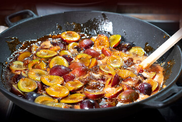 The process of boiling plum jam in a cast iron pan