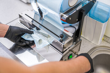 Dentist wearing protective gloves packing his equipment at the transparent packages
