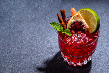 Spicy autumn pomegranate cocktail. Alcohol warming gin drink with pomegranate, lime, cinnamon,...