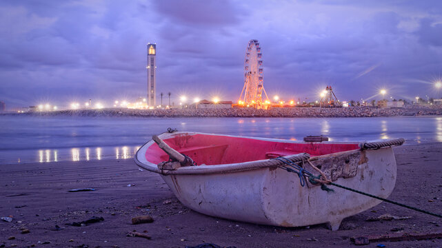 Barque sur plage avec grande mosqu&eacute;e et grande roue en fond