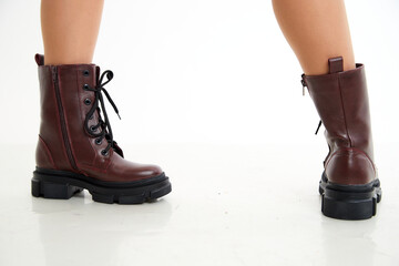 Female winter, autumn or spring brown leather shoes on leg of woman in studio on white background. Fashionable modern photography and photoshoot for a store, catalog, magazine or online