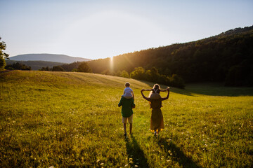 Happy young family spending time together outside in green nature.