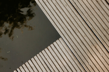 A wooden deck detail over a pond. Abstract architectural pattern detail of a timber decking in the...