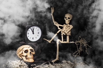 Halloween time. A skeleton crawling out of a tomb, a skull, a clock on a black, smoky, dusty...