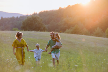 Happy young family spending time together outside in green nature.