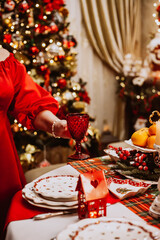 An adult woman in a red dress makes a Christmas serving at home.