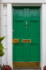 Green painted front door with white frame and brass furniture