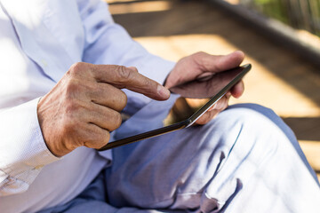 Senior man reading news on digital tablet