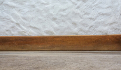 side view of a brown wooden floor with baseboard in front of a white wall. it's a blank, low-angle image. Suitable for product placement, for example for toys