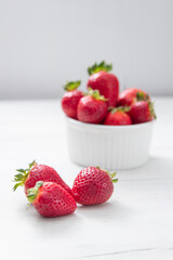 Fresh ripe delicious strawberries in a white bowl on a gray stone background
