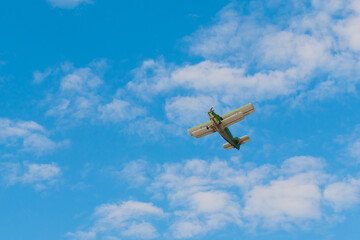 Green biplane, retro airplane flying in blue sky and doing stunts at Air Show. Performance, extreme, aerobatic, sport and aircraft concept