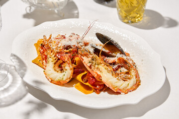 Italian cuisine - seafood pasta with shrimp and mussels in tomato sauce. Pappardelle with seafood and marinara sauce on summer day. Fine dining. Seafood pasta with langoustine and mussels.