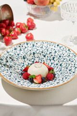 Classic panna cotta with berries on light background. Italian dessert from milk jelly - panna cotta. Desserts menu. Aesthetic composition with panna cotta and strawberries, raspberry and blueberry.
