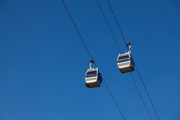 A pair of sky lift cabins in front of a clear blue sky. Tbilisi, Georgia.
